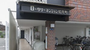 En byggnad med en överbyggd entré, en gångbana med plattor och flera cyklar parkerade utanför.