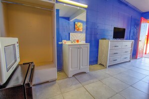 A bathroom with a white vanity, a mirror, a sink, and a television mounted on the wall. - Wheeler Inn Texas, Us - 83 By OYO (Portland)