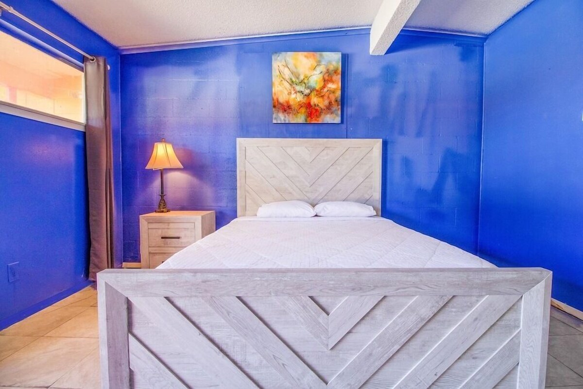 A room with a bed, a nightstand, a lamp, and a painting on the wall.