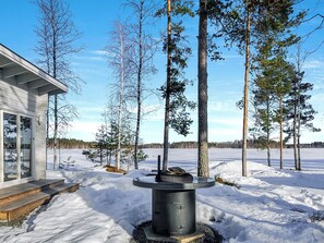 A modern house with a snow-covered yard and a fire pit in the center. - Suvituuli by Interhome (Pertunmaa)