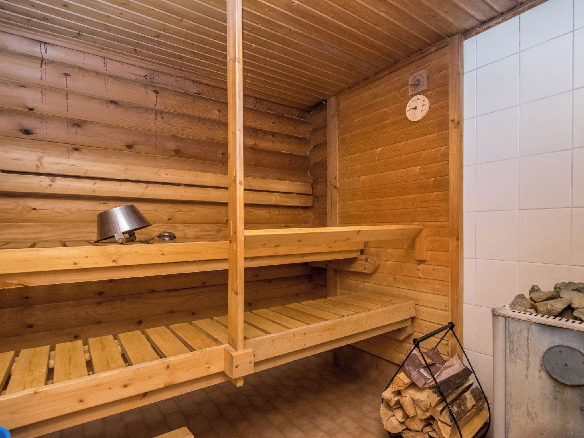 Een sauna met houten banken, een metalen kachel en een stenen muur.
