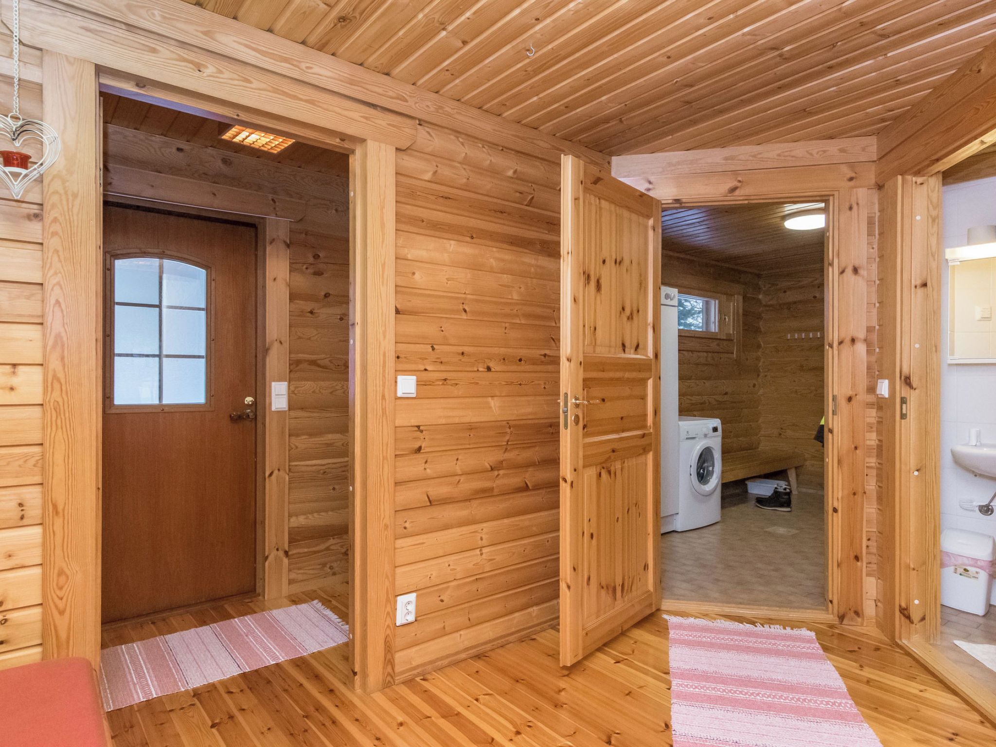 Un interno in legno con una porta, una lavatrice e un lavandino.