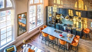 A modern kitchen with a central island, large windows, and a cozy seating area with a sofa and chairs. - Historic DC Firehouse Penthouse Loft (Washington)