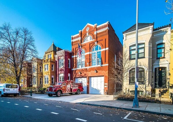 A fire truck parked in front of a red brick building with a white garage door.