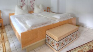 A neatly made bed with white linens and pillows, a wooden headboard, and a matching bench at the foot of the bed. - Am Dohlenberg by Interhome (Schwalenberg)