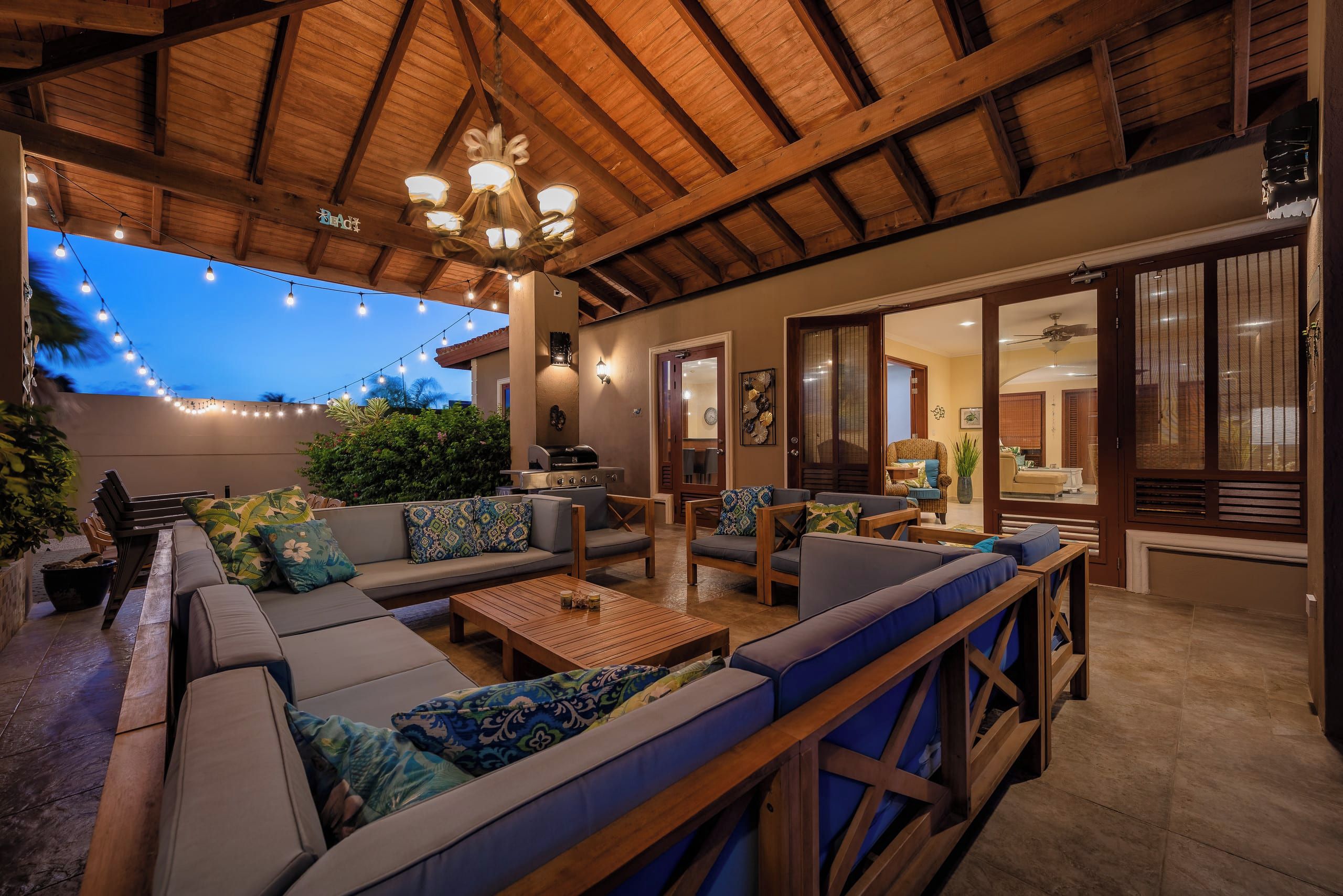Un espacio al aire libre con patio, asientos, una parrilla y luces colgantes.