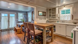 A kitchen with a wooden table and chairs, white cabinets, and a window with a view. - Wescott House in the historic Willamette District (West Linn)