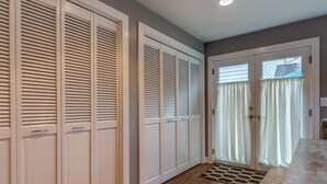 A hallway with white closets, a wooden floor, and a door with curtains. - Wescott House in the historic Willamette District (West Linn)
