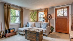 A cozy living room with a sofa, a coffee table, a fireplace, and a door. - Wescott House in the historic Willamette District (West Linn)