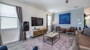 Uma sala de estar moderna com televisão de tela plana, um móvel de entretenimento branco, uma mesa de centro e duas poltronas de couro.