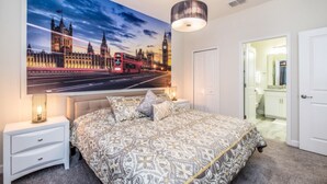 Ein Schlafzimmer mit einer großflächigen Stadtkulissen-Mural, einem Bett mit gemusterten Betttextilien, Nachttischlampen und einer Pendelleuchte.