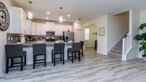 A modern kitchen with a central island, bar stools, and a staircase leading to an upper level. - 6 Bedroom 5 Bathroom 9045hs (Davenport)