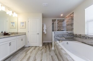 A modern bathroom with a large bathtub, a walk-in shower with a glass door, and a vanity with a granite countertop. - 6 Bedroom 5 Bathroom 9045hs (Davenport)