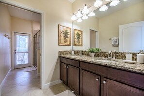 A bathroom with a double sink vanity, a large mirror, and a potted plant on the countertop. - 5 Bedroom in Champions Gate (Davenport)