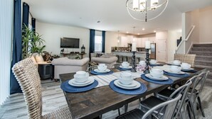 Un comedor moderno con una mesa de madera dispuesta para cuatro personas, rodeada de sillas de mimbre.