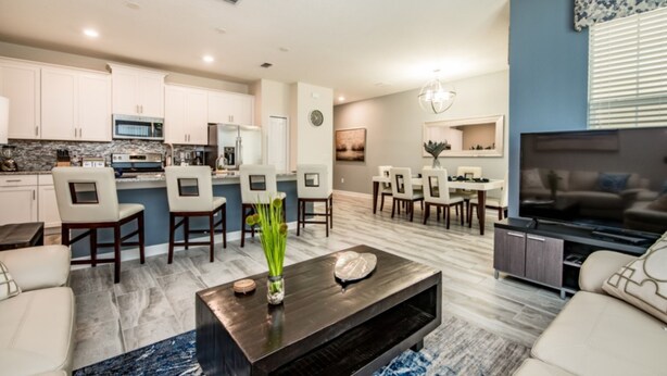 A modern living room with a dark coffee table, beige sofas, and a TV. - Champions Gate Golf Course Resort Town Home W/pool (Davenport)