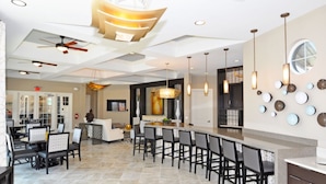 A spacious dining area with a long counter and multiple chairs, a ceiling fan, and pendant lighting. - Solterra Resort Villa (Davenport)