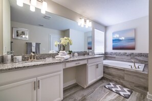 Un baño moderno con un espejo grande, tocador, lavabo y bañera.