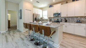 A modern kitchen with white cabinets, a granite countertop, and stainless steel appliances. - Ultimate 5 Bedroom 5 Bathroom Property (Kissimmee)