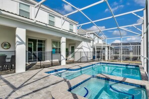 Ein Schwimmbeckenbereich mit einer verglasten Struktur, einer Terrasse mit Stühlen und Blick zum Himmel.
