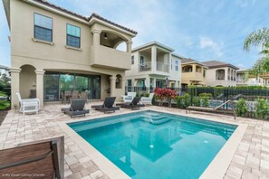 A residential property with a swimming pool, outdoor seating, and a two-story building. - Castle Pines Villa Reunion (Kissimmee)