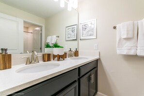 A bathroom with two sinks, a large mirror, and a towel rack. - Plunker Drive Villa Champions Gate (Davenport)