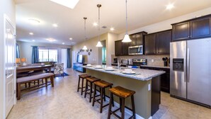 A spacious kitchen with dark cabinets, stainless steel appliances, and a central island with stools.