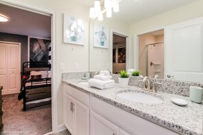A modern bathroom with a granite countertop, two sinks, a large mirror, and a bench in the corner. - Champions Gate 6bed 5bath Vacation Home 9022sd (Davenport)