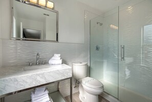 A modern bathroom with a marble sink, a toilet, and a glass-enclosed shower. - Oasis Key Villa Emerald Island (Kissimmee)