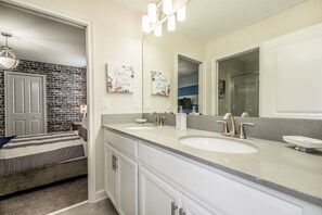 A bathroom with a double sink, a large mirror, and a shower area. - 8903sd Champions Gate 6 Bedroom 5 Bathroom Villa (Davenport)