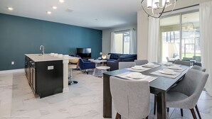 A modern kitchen with a dining area, a TV, and a sofa. - Stinger Drive Villa Champions Gate 2 (Davenport)