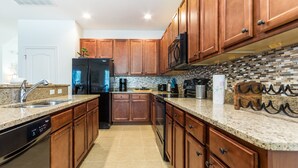 A modern kitchen with wooden cabinets, granite countertops, stainless steel appliances, and a tiled backsplash. - 5244oa Luxury 6 Bedroom 4.bath Home With Spa (Davenport)
