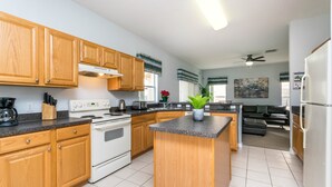Cocina moderna con armarios de madera, una isla central y un comedor con sofá negro.