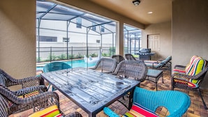 A covered patio area with wicker furniture, a pool, and a grill. - 8952rs Luxury 7 Bed Villa With Saltwater Pool/spa (Kissimmee)
