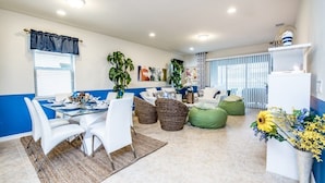 A modern living room with a glass dining table, white chairs, and green bean bags. - 8952rs Luxury 7 Bed Villa With Saltwater Pool/spa (Kissimmee)