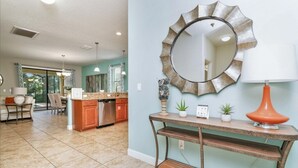 A spacious kitchen with a dining area, a large mirror, and a console table with a lamp. - Showhome 5 Bedroom Champions Gate Villa 1401mvd (Davenport)