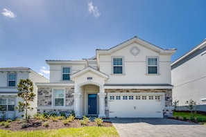 A two-story house with a stone facade, a blue door, and a garage.