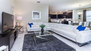 A modern living room with a sectional sofa, a glass coffee table, and a flat-screen TV.