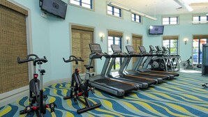 Ein Fitnessstudio mit Laufbändern, Ergometer und einem gemusterten Teppich.