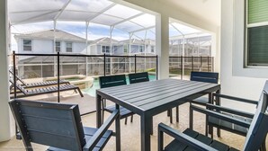A covered patio with a pool, outdoor seating, and a view of neighboring houses. - 1565tl Champions Gate Furnished 6 Bedroom (Davenport)