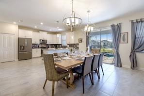 A modern kitchen with white cabinets, stainless steel appliances, and a dining area with a table set for four.