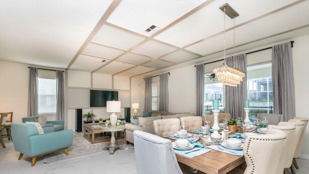 A spacious living room with a sofa, a dining table set for six, and a television. - 1574ol Ultimate 8 Bedroom (Davenport)
