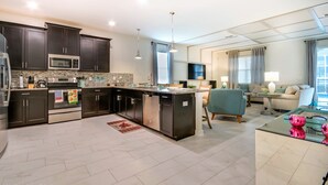 A modern kitchen with dark cabinetry, stainless steel appliances, and a central island. - 1574ol Ultimate 8 Bedroom (Davenport)