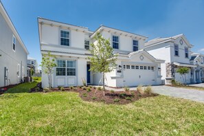 A two-story residential building with a white exterior, a garage, and a well-maintained lawn. - 1596san Champions Gate (Davenport)