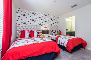 A bedroom with two beds, each with Mickey Mouse themed bedding.