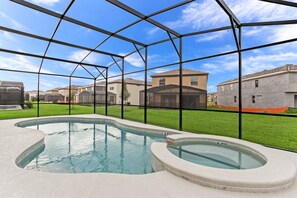 A swimming pool with a glass enclosure, surrounded by a grassy area and residential buildings.