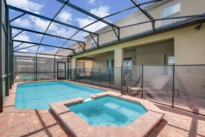Une piscine intérieure dotée d’un jacuzzi, entourée d’une structure en verre et recouverte d’un sol en briques.