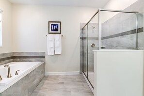 A modern bathroom with a glass-enclosed shower, a freestanding bathtub, and a framed artwork on the wall. - 1594sand Amazing Champions Gate 8 Bedroom 5 Bath (Davenport)