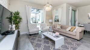 A living room with a TV, two armchairs, a sofa, a coffee table, and a chandelier. - Sanbagger Drive Villa 1581 Champions Gate (Davenport)