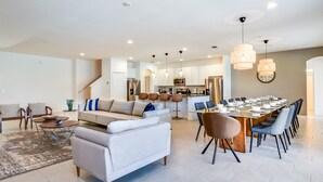 Un vaste espace de vie comprenant un canapé, une table basse et une table à manger, le tout prêt pour prendre un repas.